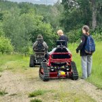 Two Adaptive track chairs going down a hiking path. Adaptive track chairs are able to traverse various terrains that the average wheelchairs cannot.