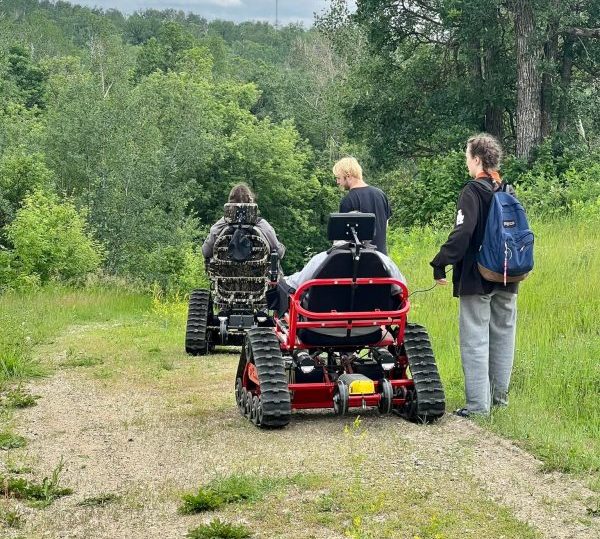 Two Adaptive track chairs going down a hiking path. Adaptive track chairs are able to traverse various terrains that the average wheelchairs cannot.